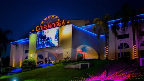 Entrada del Casino Victoria en Victoria, Entre Ríos, iluminada de noche con pantalla LED y palmeras