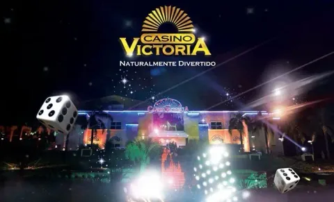 Fachada del Casino Victoria iluminada de noche, con el logotipo y el lema Naturalmente Divertido